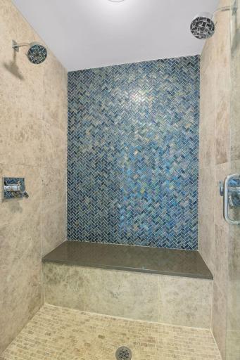 Primary walk-in shower with deep bench and double shower heads.