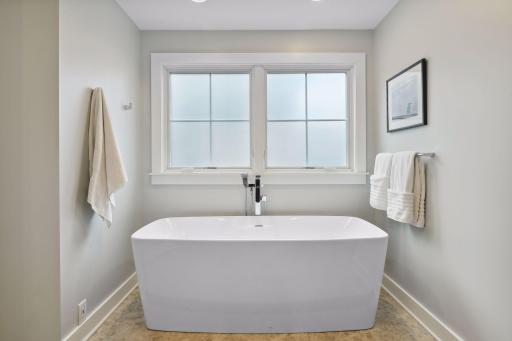 Primary bath soaking tub. Privacy windows allow natural light in the bathroom.