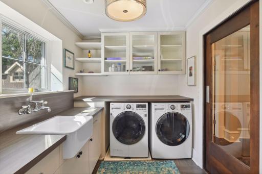 Beautifully appointed second level laundry room with windows over the farmhouse style apron sink. Excellent storage and counter space. Wood framed pocket door with glass panel.