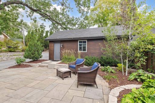 Low maintenance back yard with stone paver patio, garden beds, and attractive landscaping.