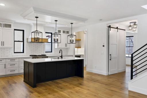 Modern kitchen with large central island, professional style appliances, quartz countertops, and custom cabinetry will please any chef. Pictures of previously built house.