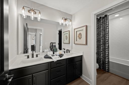 Again, the hall bath exudes luxury with sleek black cabinetry & faucets, elevated lighting, and lovely tiled bath surround.