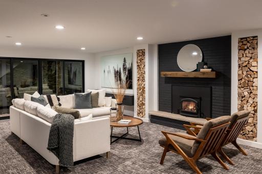 The lower level family room has a walk-out to nature, a storage bench/drop zone near the garage/entrance, a wood-burning fireplace and eye-catching design choices.