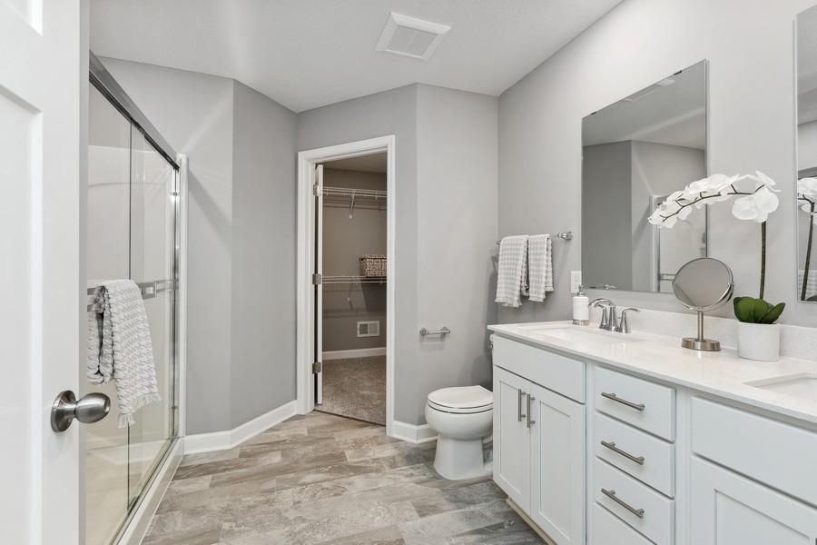 An extension of the owner's suite, this private and spacious bath contains a double-vanity, a large shower and a walk-in closet. (Photo of decorated model, actual home's finishes may vary slightly)