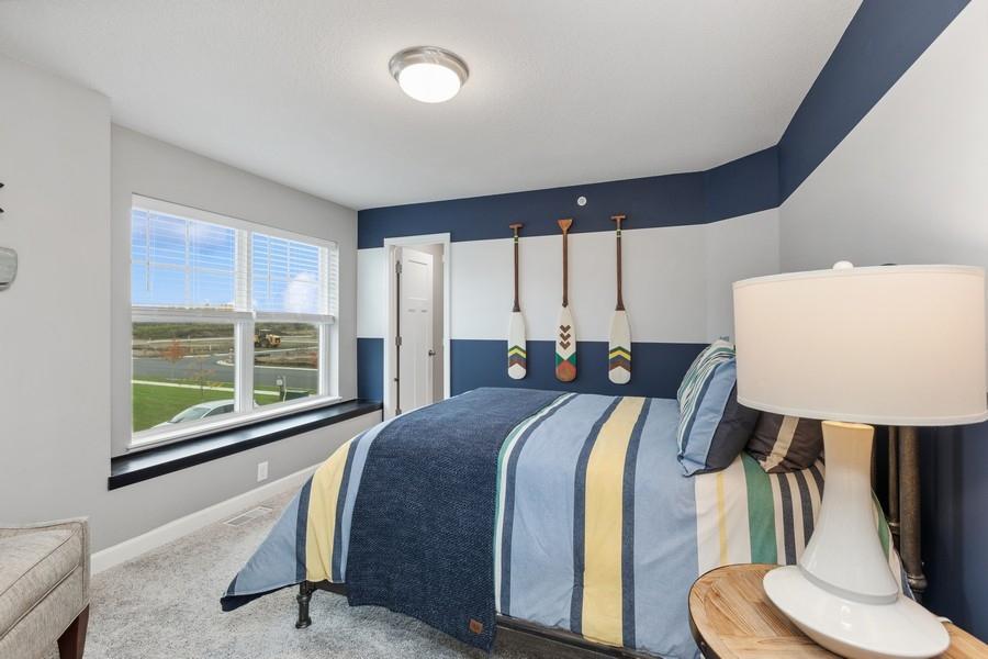 The second generously sized upper level secondary bedroom with a spacious closet and a window ledge. (Photo of decorated model, actual home's finishes may vary slightly)