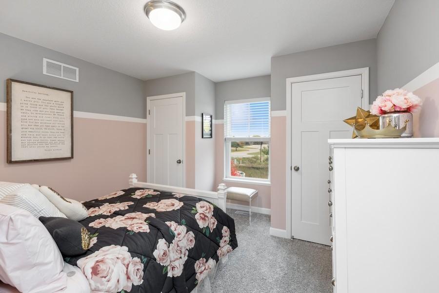 One of two generously sized upper level secondary bedrooms. This one even features two spacious closets! (Photo of decorated model, actual home's finishes may vary slightly)