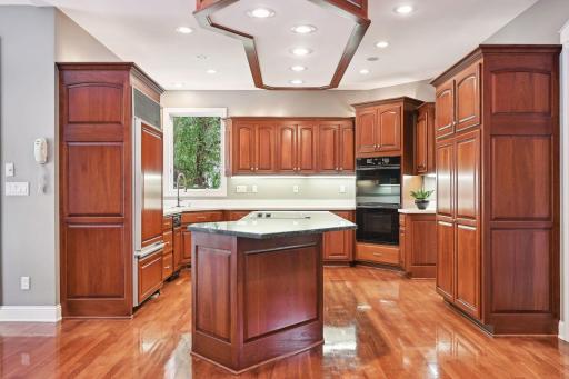 Gleaming wood floors complement custom cherry cabinetry. Built-in SUB-ZERO refrigerator. Granite countertop, 5-burner glass top stove, double oven, dishwasher, trash compactor, undermount lighting, double window over sink, pullout pantry storage.