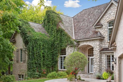 An enchanting wall of ivy texturizes the stately facade of brick & stone. 2020 installed 60-year cedar shakes are a rich enhancement & investment to the exterior.