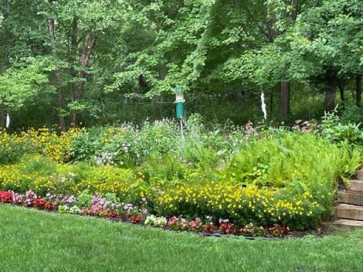 The yard is filled with beautiful flowers and landscaping.