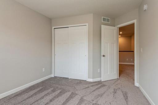 One of the generously sized secondary bedrooms with a spacious closet. (Photos are not of actual home. Actual home will be similar. Some colors and features may vary.)