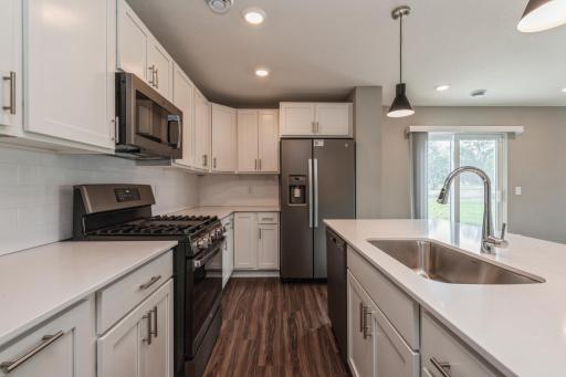 Equipped with gorgeous kitchen appliances, quartz countertops, a kitchen island and plank-style flooring throughout, this kitchen adds distinction & character to the home. *Photos are of another home, colors and finishes may vary.