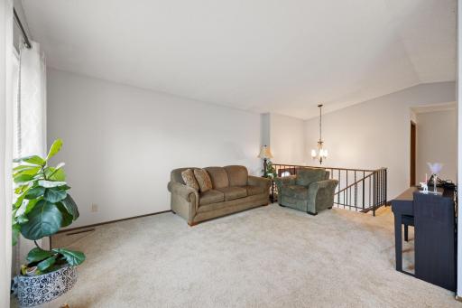 Spacious main level living room with plush carpet and a vaulted ceiling.