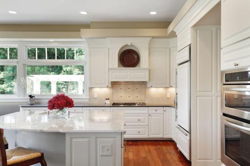 The quartzite is an off white with gray and charcoal veining. Subzero refrigerator and Wolfe 5 gas burner cooktop. The backsplash is a hand tumbled ceramic tile with a crackled, glazed finish.