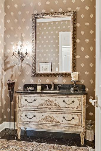 Power room with marble top vanity and marble floors.