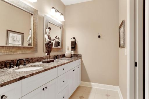 The east lower level bath with marble tops and double sink vanity. The shower and toilet are adjacent to the right.
