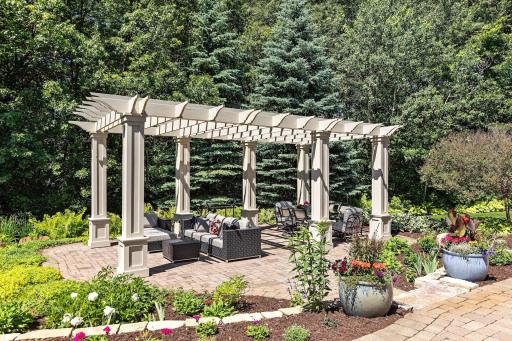 The pergola with a seating area overlooking the pond and a dining area.