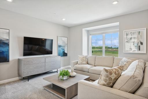 Elegant windows provide an abundance of natural light to flow throughout the main level, including in this nicely sized family room. (Photo of decorated model, actual home's finishes may vary slightly)