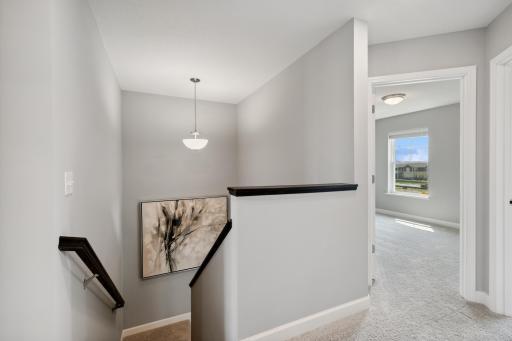 The staircase leads to the upper level featuring three bedrooms and two bathrooms. (Photo of decorated model, actual home's finishes may vary slightly)
