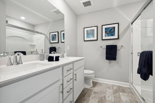 Relax in your private oasis featuring a double-vanity and large shower. (Photo of decorated model, actual home's finishes may vary slightly)