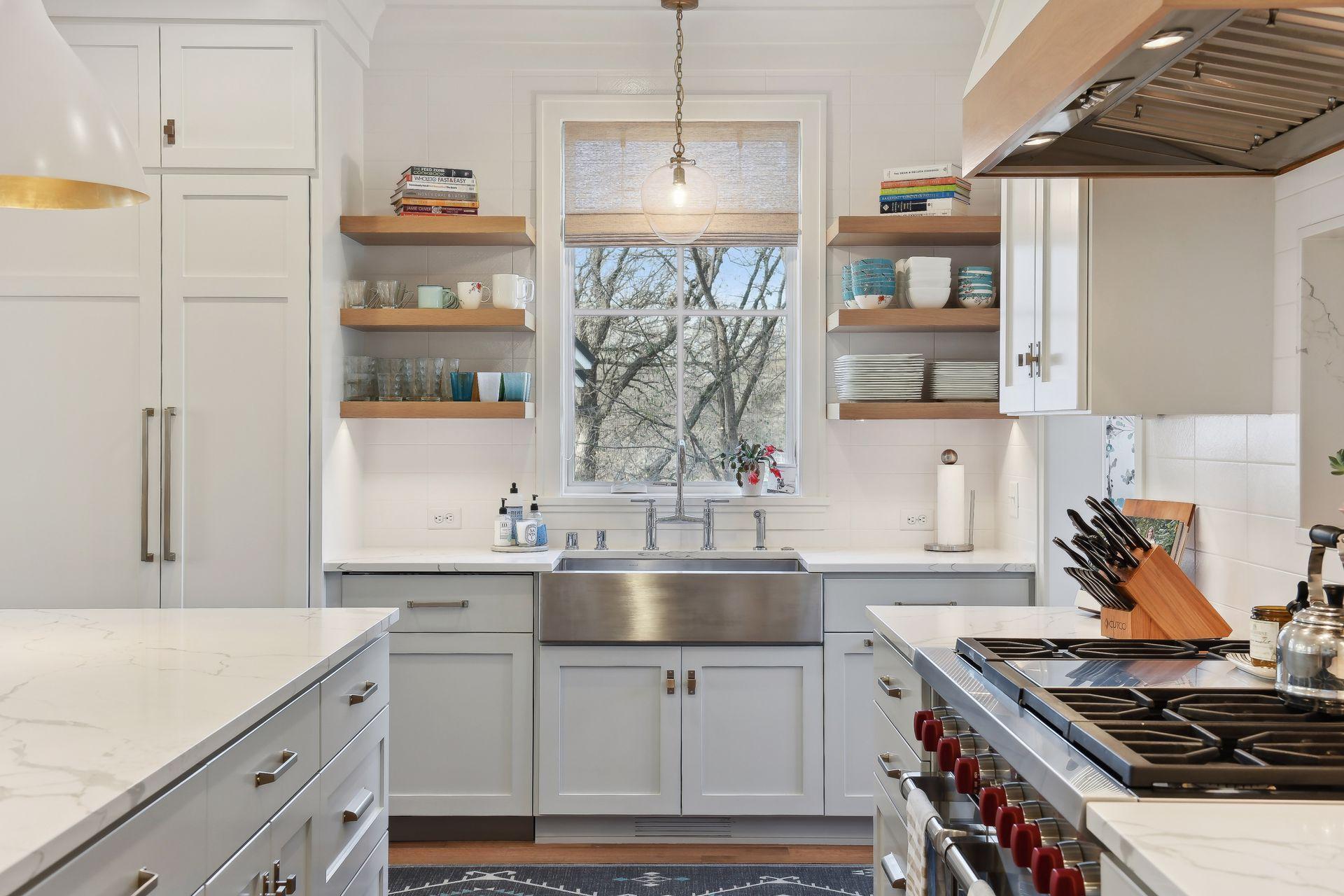 The stainless farm sink overlooks the beauty of the backyard. While floating shelves provide easy access to serve ware.