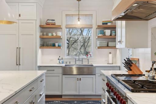 The stainless farm sink overlooks the beauty of the backyard. While floating shelves provide easy access to serve ware.