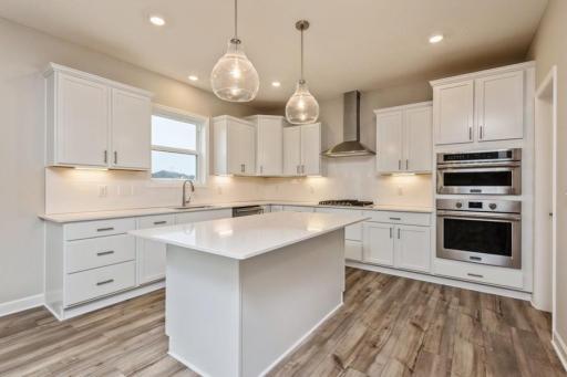 The spacious kitchen features a sizable pantry, quartz counters, stainless appliances, including an oven with convection cooking and a gas cooktop.