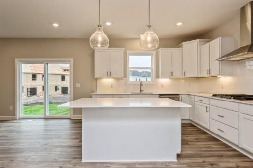 The spacious kitchen features quartz counters, stainless appliances, including an oven with convection cooking and a gas cooktop.