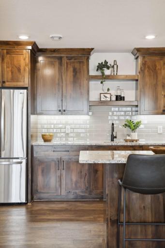 Gorgeous custom cabinetry and a tile back splash accent the custom hardware and lighting.