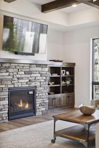 A Stunning Stone fireplace offers an upgraded gas fireplace flanked by custom built ins.