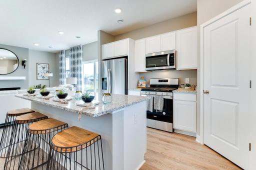 Stunning AND functional all in one, as the kitchen space features a pantry closet for help with storage - and an oversized island coated in Quartz countertops with an overhang for seating! (Photo of model, colors may vary)