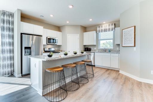 A kitchen built to perform - complete with an oversized island, pantry closet, stainless appliance package including a vented microhood and gas range, and enough space throughout for the family chef to roam about! (Photo of model, colors may vary)