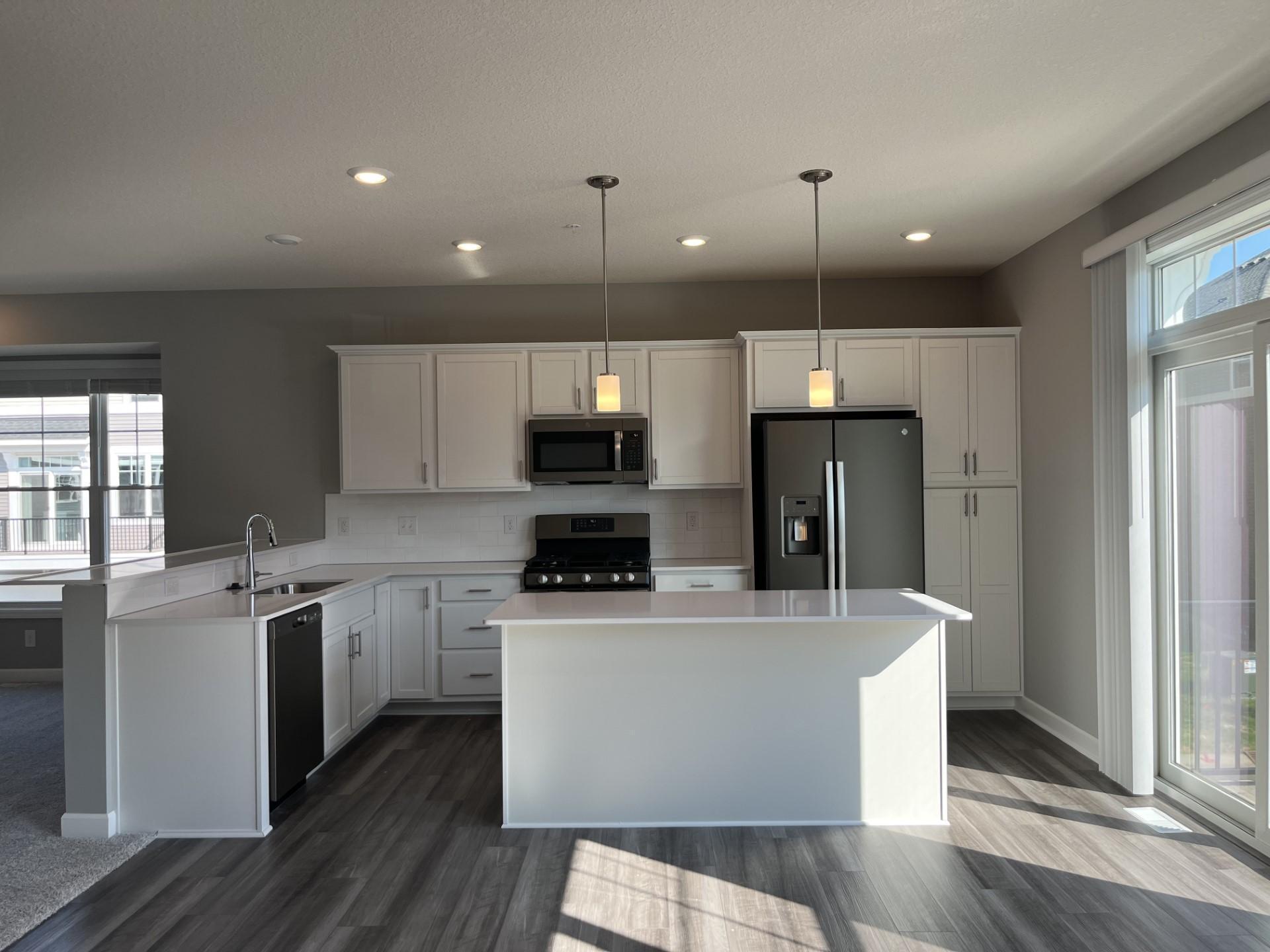This spacious kitchen features a large center island, quartz kitchen counters, under mount sink, LED lighting, LVP flooring, slate appliances and more!