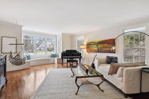 The light-filled living room features gleaming hardwood floors, a cozy window seat, and beautiful details like cove moldings.