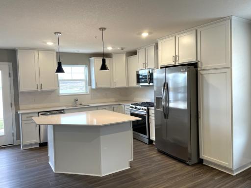 The kitchen is home to a large center island complete with quartz countertops, stainless appliances and a luxurious gas cooktop.