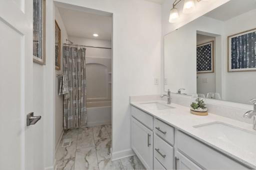 Featuring a double-vanity, this secondary bath is sure to keep everyone moving during those busy mornings. (Photo of decorated model, actual home's finishes may vary slightly)