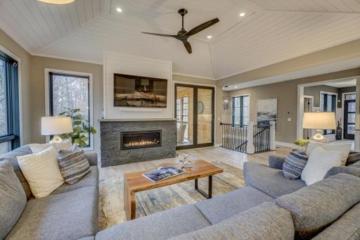 Relax by the stone fireplace and custom raised tray-vault shiplap ceiling