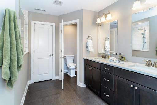 Spa Like Primary Bathroom with Glass Walk In Shower, Double Sinks, Linen Closet and Separate Room with Stool.
