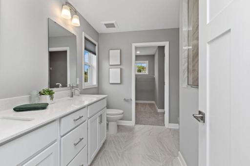 An extension of the primary suite, this private and spacious bath features a dual-vanity, a serenity shower and access to the walk-in closet. (Photo is of a decorated model, actual homes features may vary)
