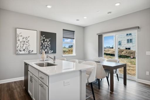 Enjoy plenty of seating at the kitchen island and dining area adjacent to the kitchen. Perfect for entertaining or having a family meal together. (Photo of decorated model, actual home's finishes may vary slightly)