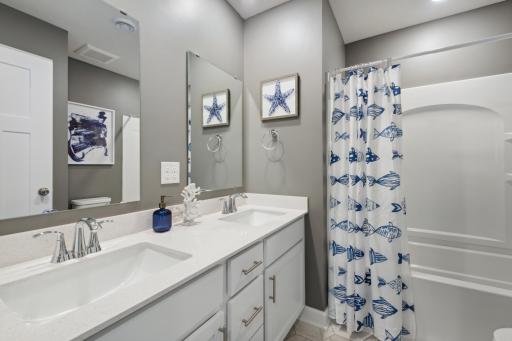 Featuring a double-vanity and linen closet, this secondary bath is sure to keep everyone moving during those busy mornings! (Photo of decorated model, actual home's finishes may vary slightly)