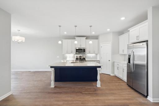The kitchen is complete with stainless GE appliances, white maple cabinetry and quartz counters accented by stainless finishes.