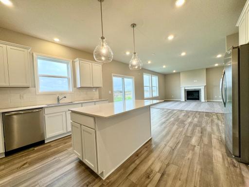 This spacious kitchen features a walk-in pantry, quartz countertops, recessed lighting, LVP wood floors, stainless appliances and more! Photos of similar home, actual colors and finishes may vary.