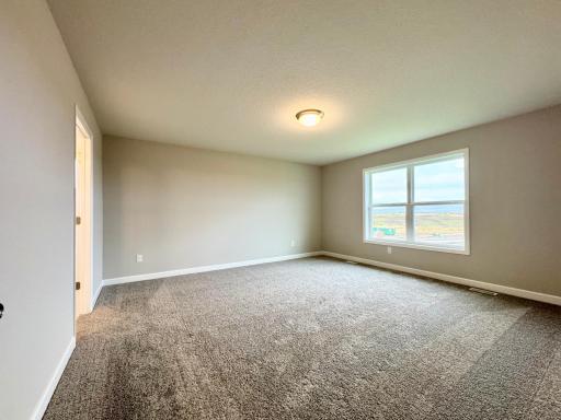 The spacious owner's suite with tons of natural light, the perfect place to relax. Photos of similar home, actual colors and finishes may vary.