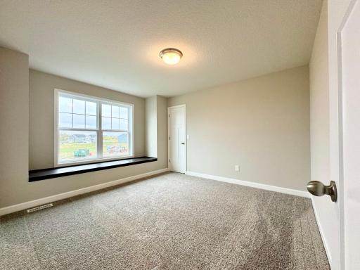 One of four upper level bedrooms, all with walk in closets! This one features a window seat. Photos of similar home, actual colors and finishes may vary.
