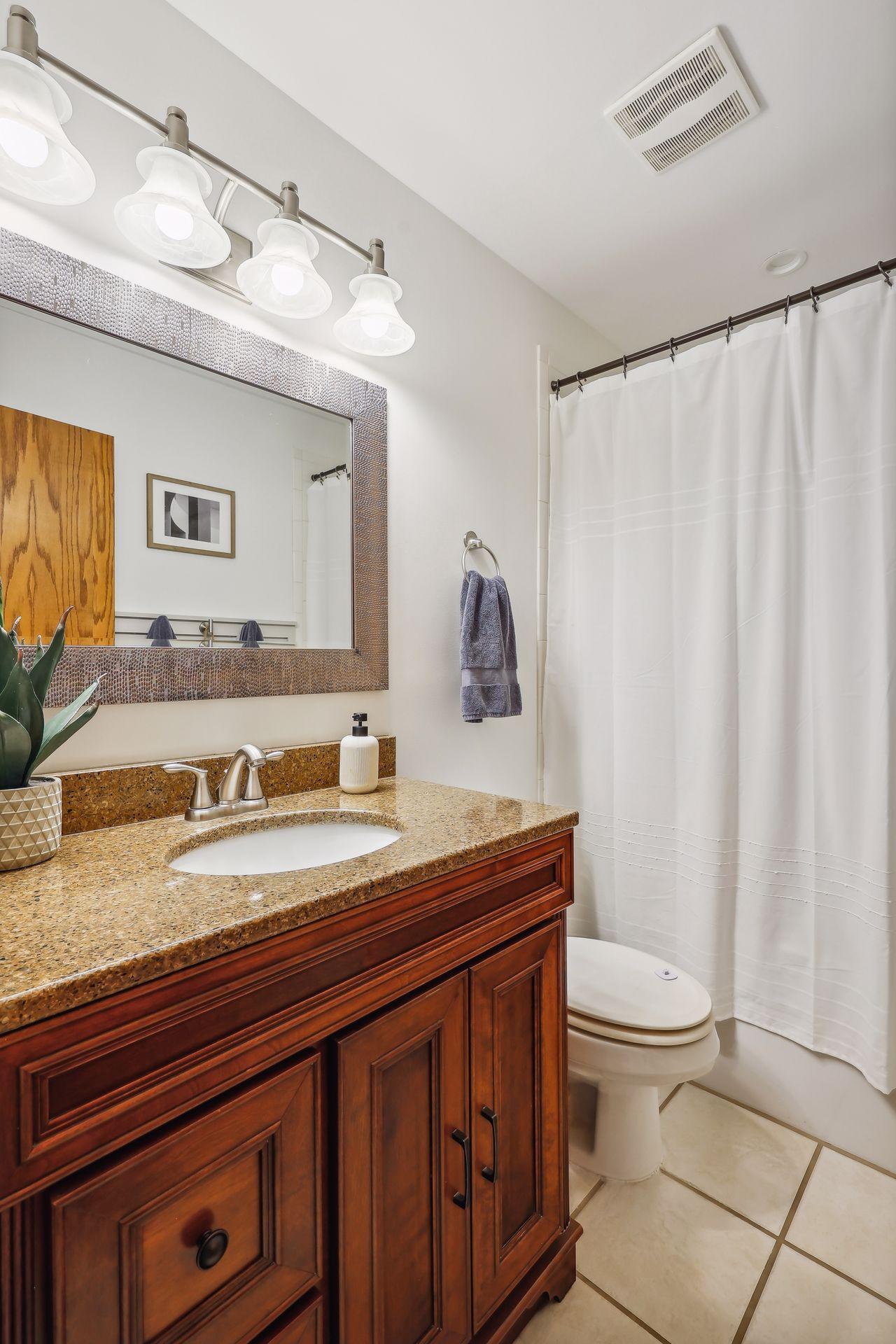 Upper level updated bathroom with tile floors, granite counter, and wainscoting accent wall.