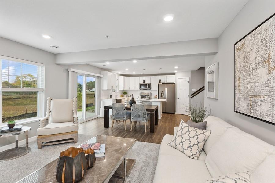 The spacious great room seamlessly connects to the kitchen area, perfect for entertaining. It also features many large windows providing warm natural light. (Photo of decorated model, actual home's finishes may vary slightly)