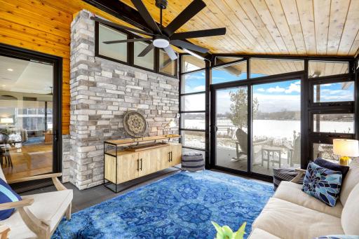 Main level glass enclosed sunroom with stone accent wall and wood ceiling