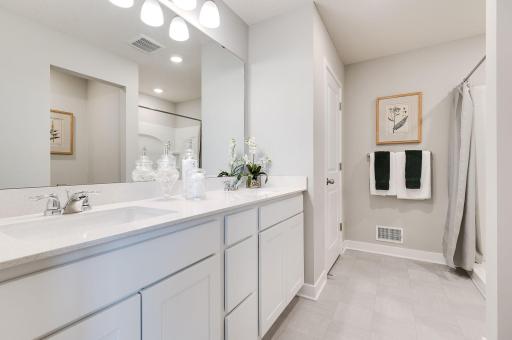The attached primary bathroom makes getting ready to go fun! It features a double quartz vanity, linen closet, walk-in shower and separated toilet. (Model home, colors will vary)