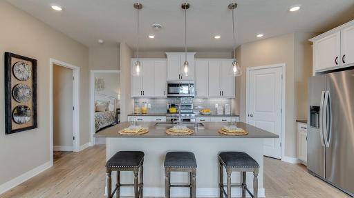 Open concept kitchen with ample countertop space and a large corner pantry. Model photo. Options and colors will vary. See listing agent for home specific selections.