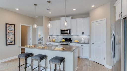 Open concept kitchen with ample countertop space and a large corner pantry. Model photo. Options and colors will vary. See listing agent for home specific selections.